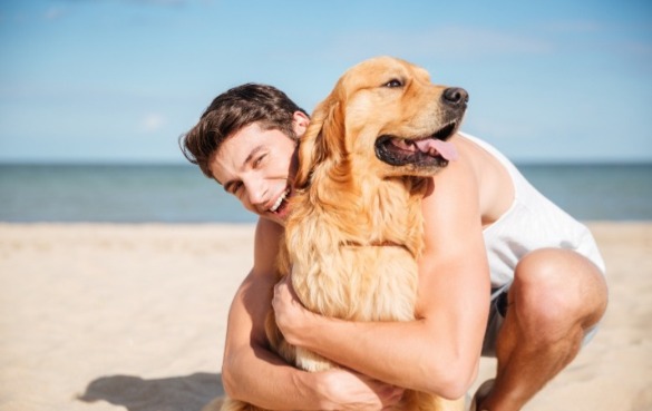 Man hugging his dog on the beach | Sun-Surf Vacation Rentals Emerald Isle