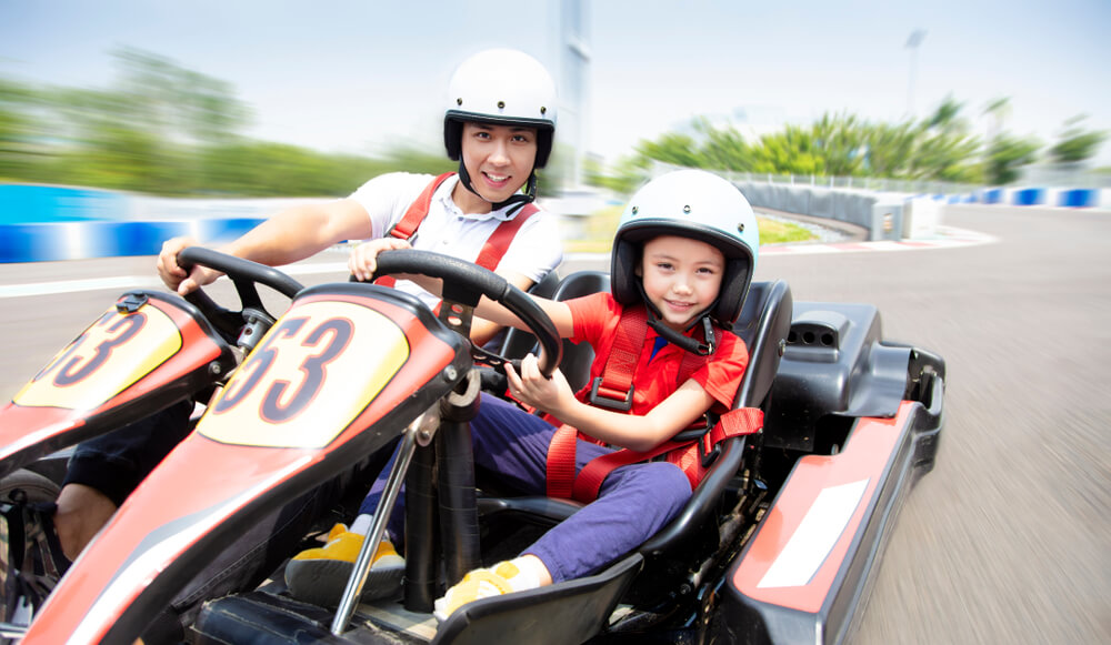 A father and their child racing go karts in Emerald Isle.